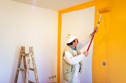 Pintor aplicando pintura amarilla en una pared